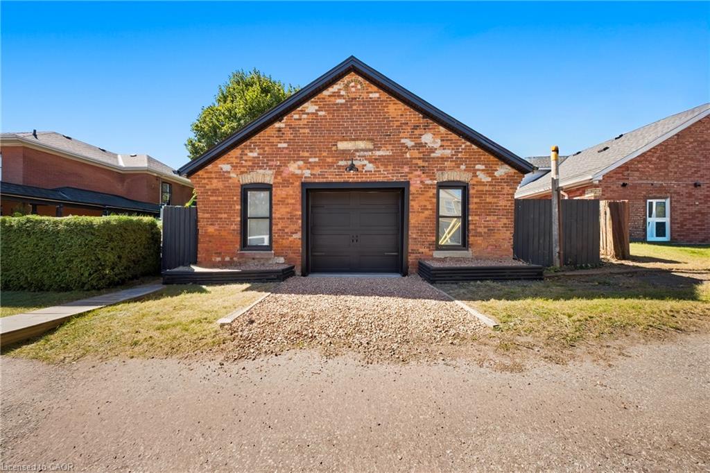Red brick gabled building with a dark garage door and gravel driveway.
