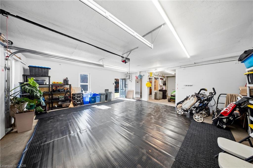Spacious garage with black floor covering, storage shelves, bicycles, and a stroller.