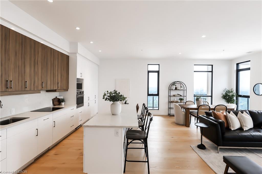 Open-plan condo kitchen with walnut cabinets, a large island, and adjoining dining and living areas.