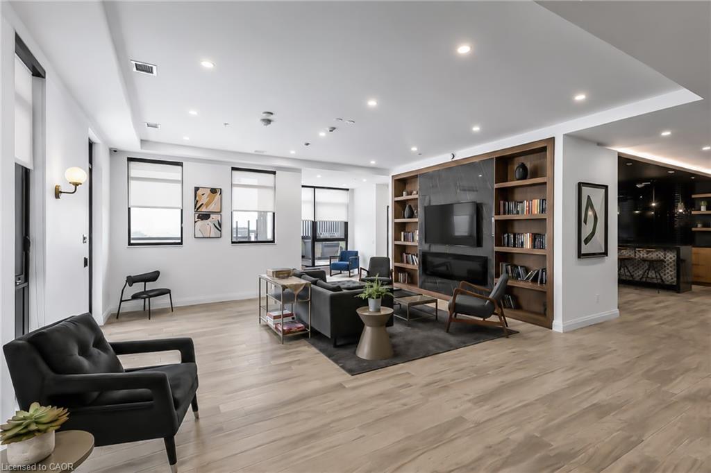 Furnished condo living room with a dark sectional, large windows, and built-in media shelving.