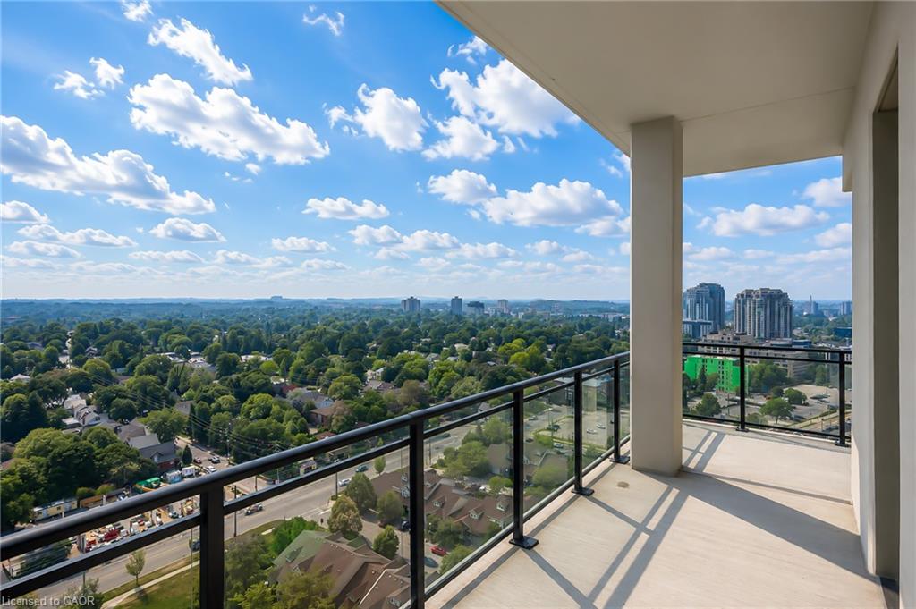 Condo balcony overlooking leafy Waterloo neighborhoods and distant high-rise buildings.