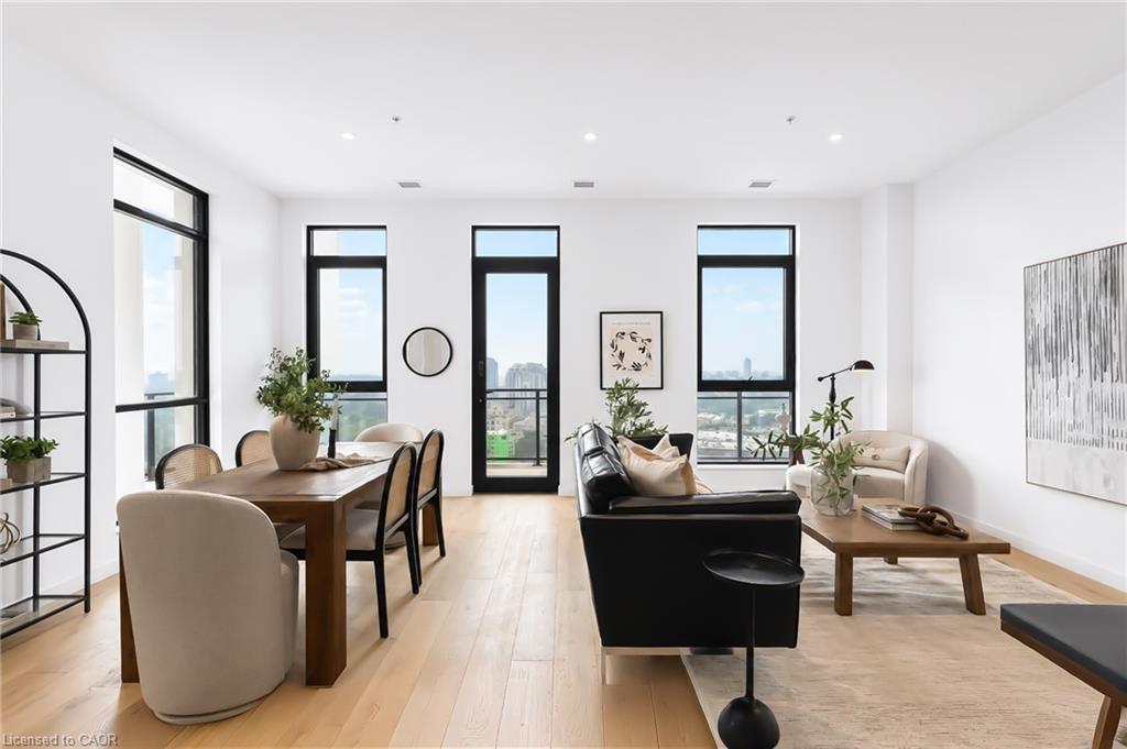 Staged condo living and dining area with large windows overlooking the city.