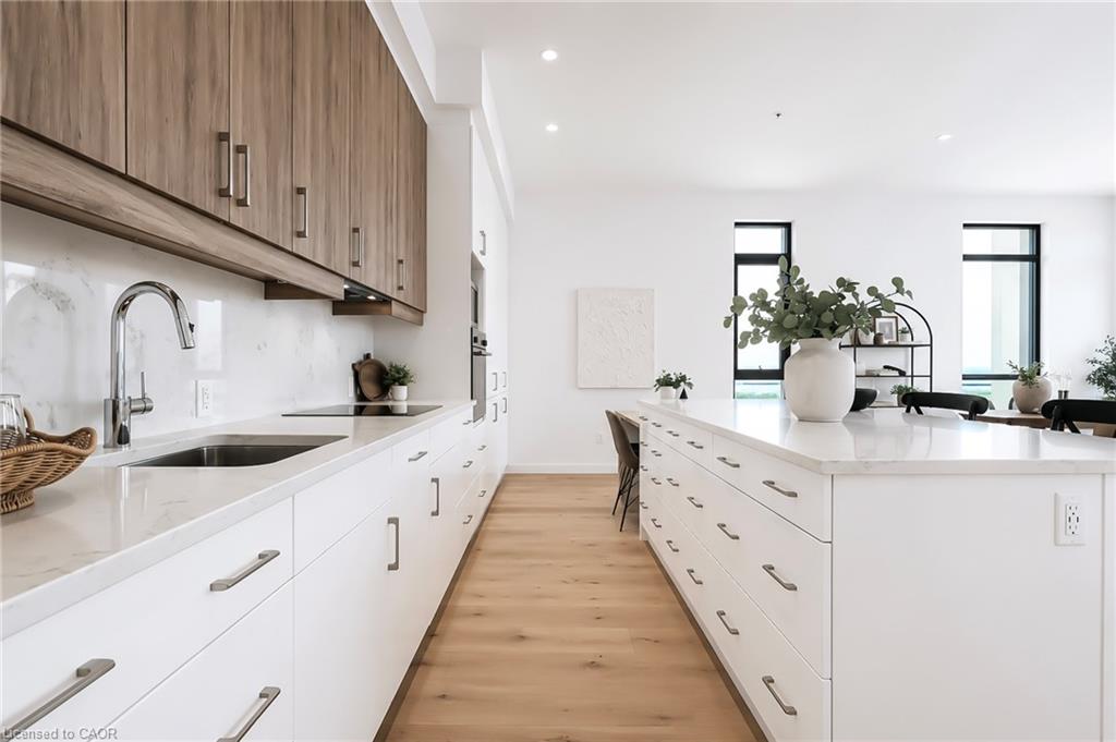 Modern kitchen with a large white island, wood upper cabinets, and light wood flooring.