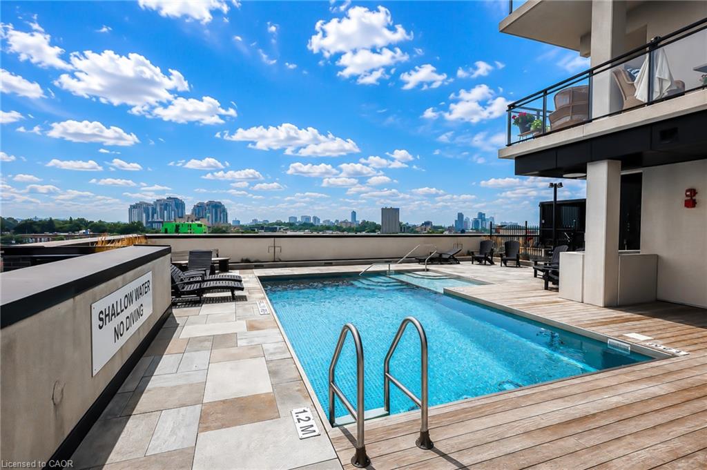 Rooftop pool with tiled deck, lounge chairs, and a city skyline in the distance.