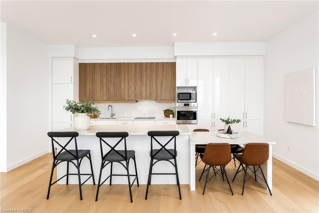 Open-plan kitchen with a large island, wood accent cabinets, and an adjacent dining table.