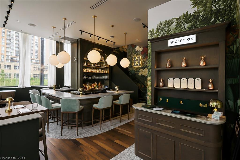 Furnished reception lounge with a dark wood desk, green chairs, and a built-in bar.