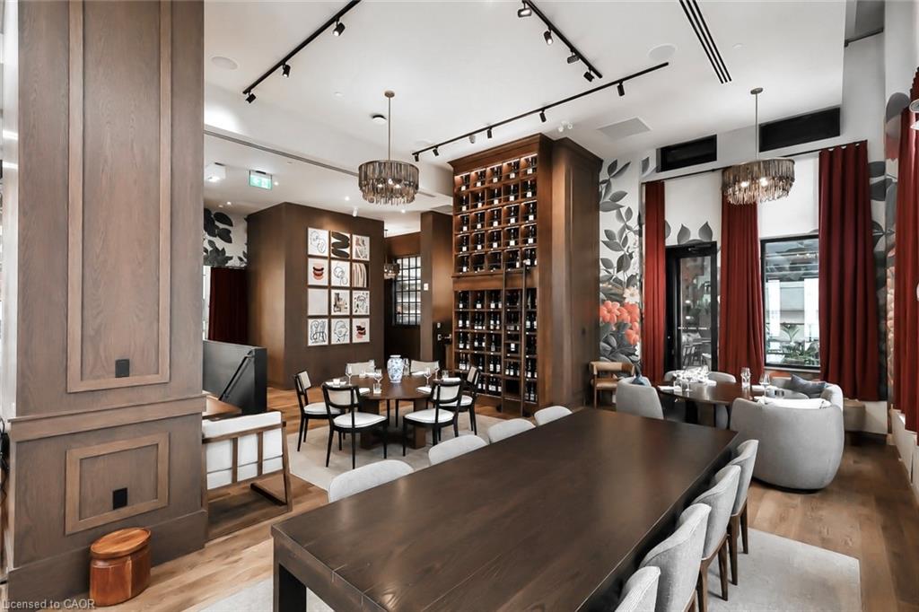 Dining room with a long wood table, built-in wine shelves, chandeliers, and red curtains.
