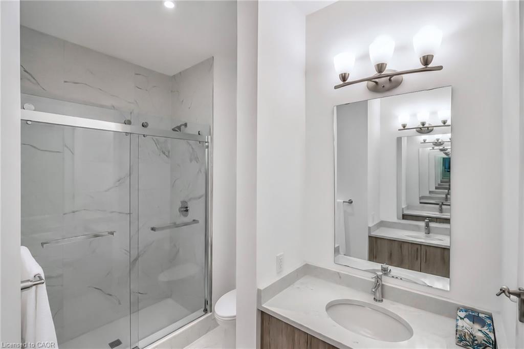 Modern bathroom with a marble-look glass shower and wood-grain vanity.
