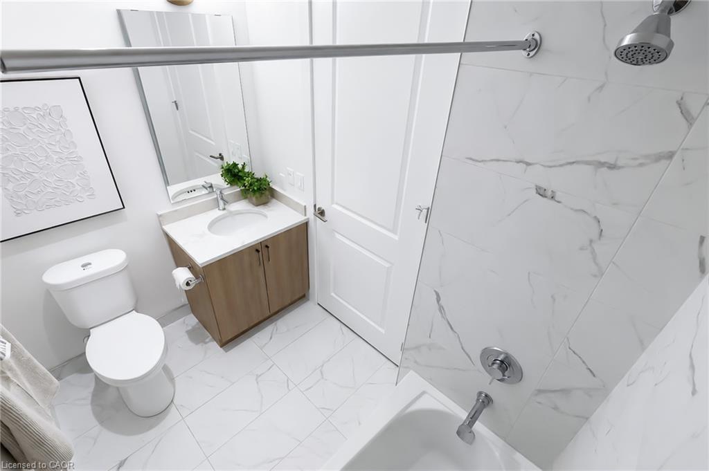Bathroom with a wood vanity and sink beside a marble-look tiled tub-shower.