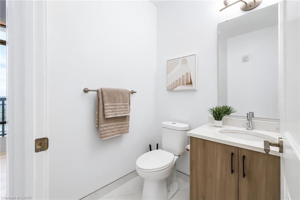 Bright bathroom with a wood-front vanity, white countertop, large mirror, and toilet.