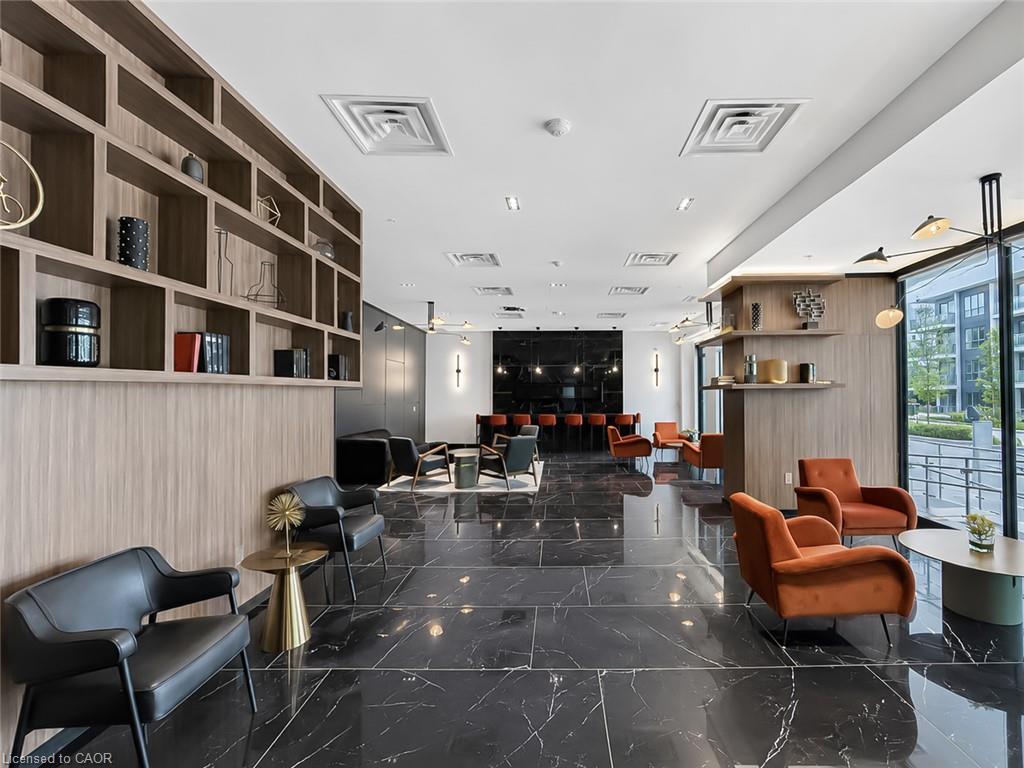 Furnished condominium lobby with black marble flooring, wood shelving, and orange lounge chairs.