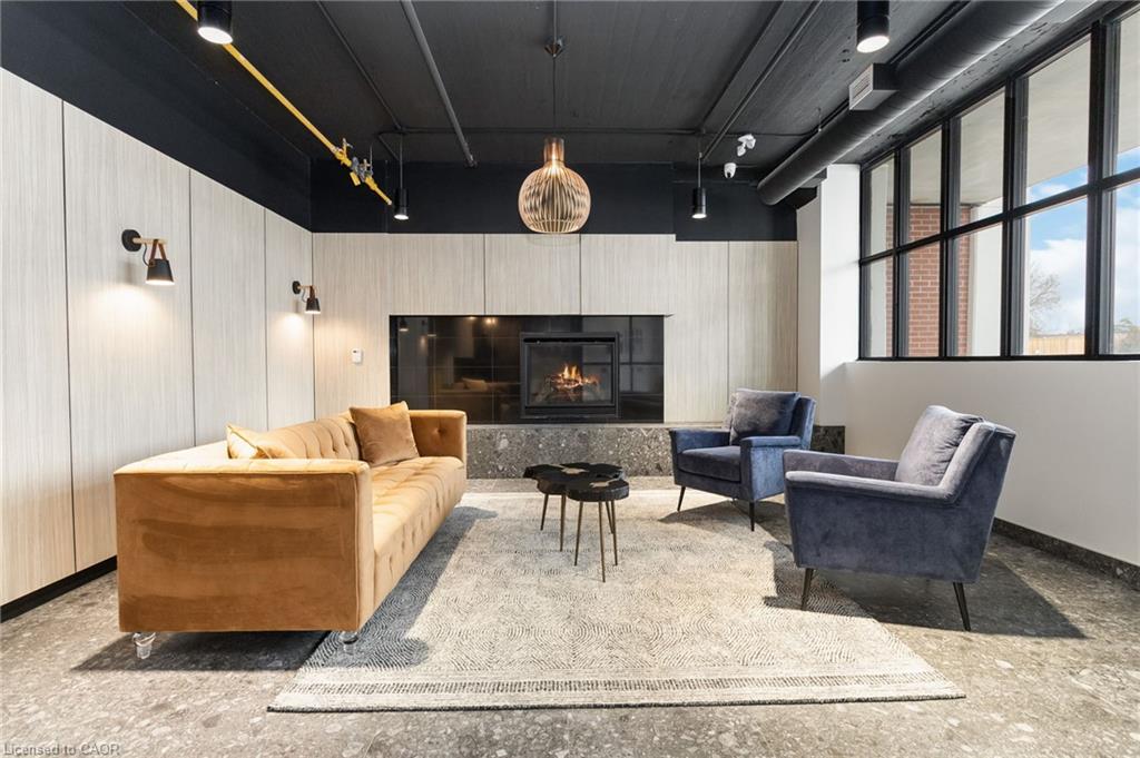 Furnished resident lounge with a fireplace, tan sofa, and blue armchairs.
