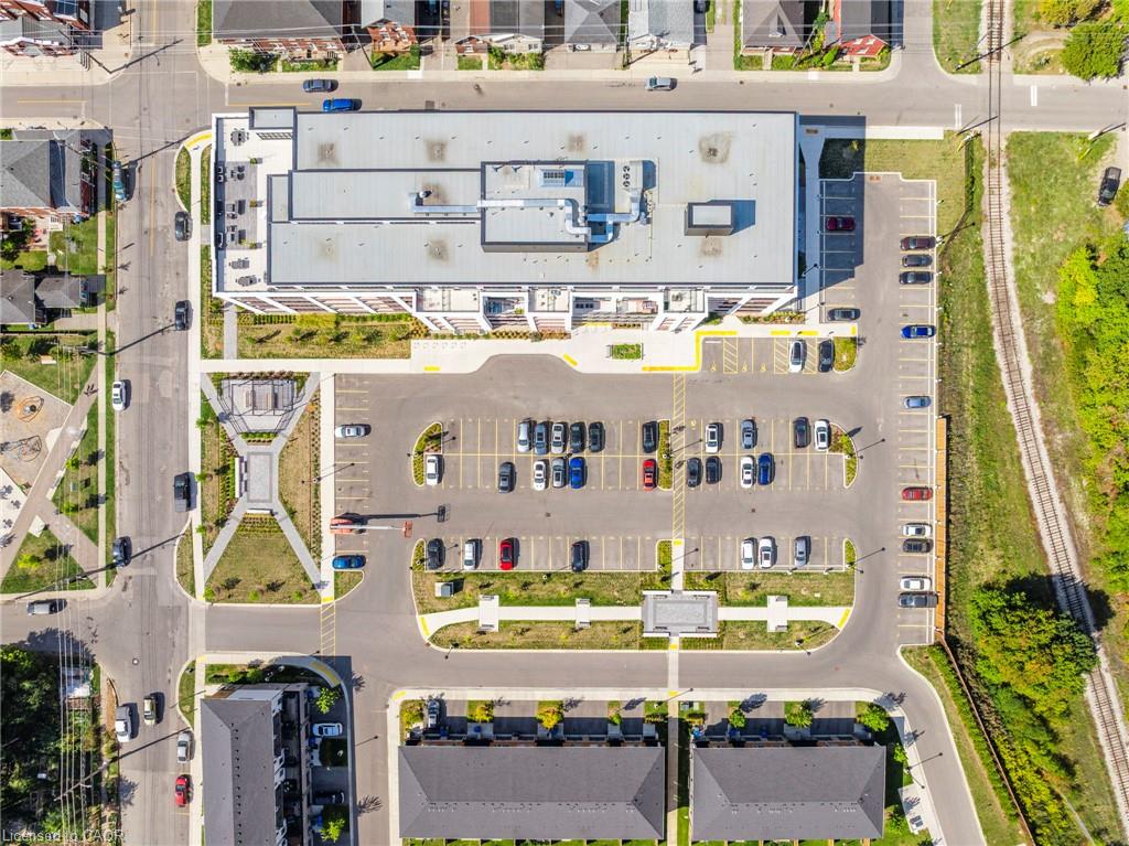 Aerial view of a condominium building and its parking lot, with a railway along one side.
