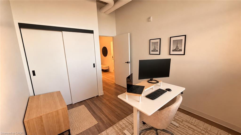 Home office with a white desk, computer setup, and sliding-door closet.