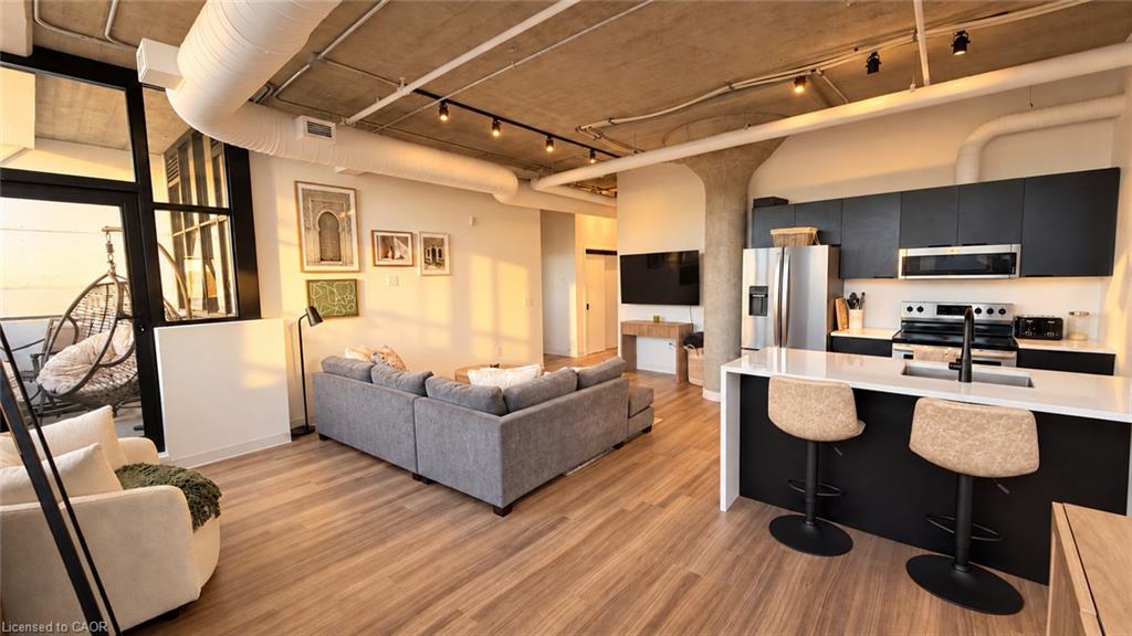 Open-concept living room and kitchen with a gray sectional, black cabinetry, and island seating.