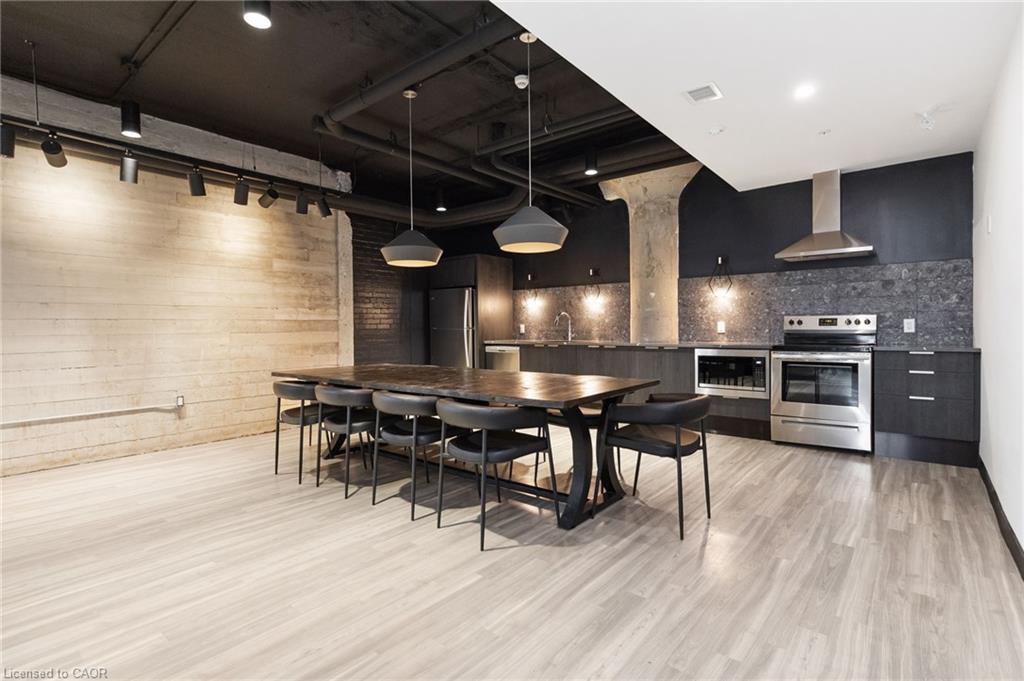 Open-concept kitchen and dining area with dark cabinetry, exposed ceiling, and a long dining table.