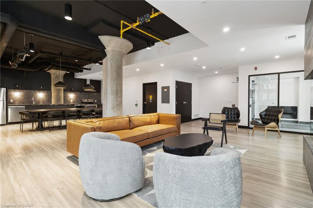 Furnished condo amenity lounge with a communal kitchen, tan sofa, and modern seating.