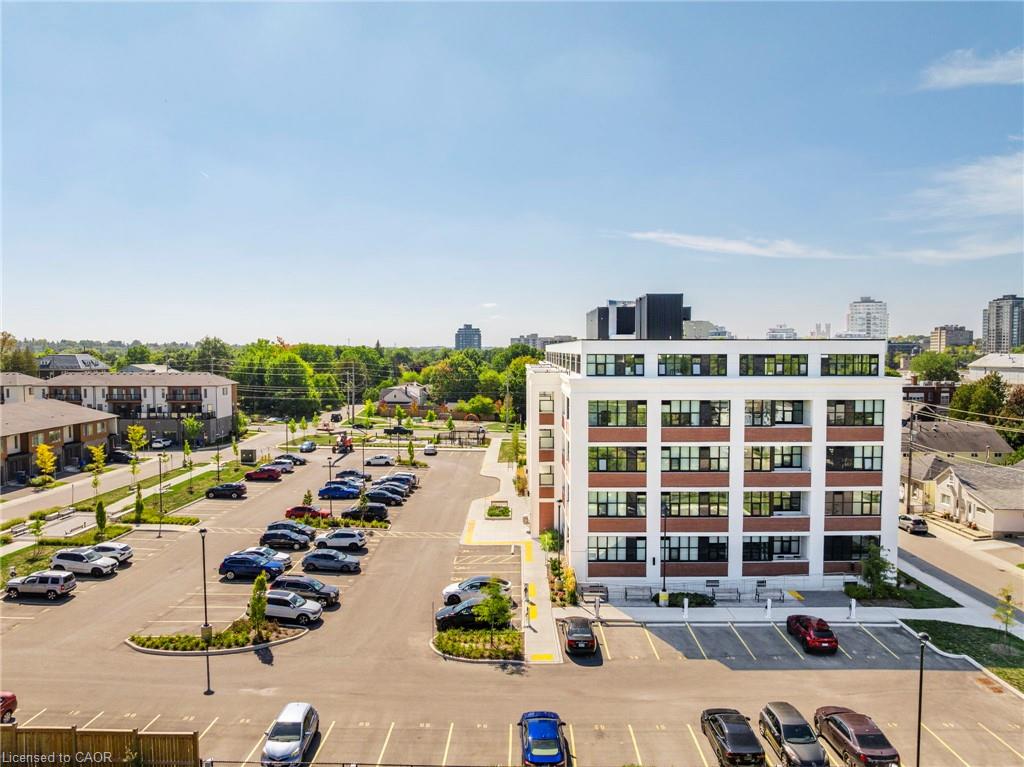Modern white-and-brick low-rise building beside a large parking lot and surrounding homes.