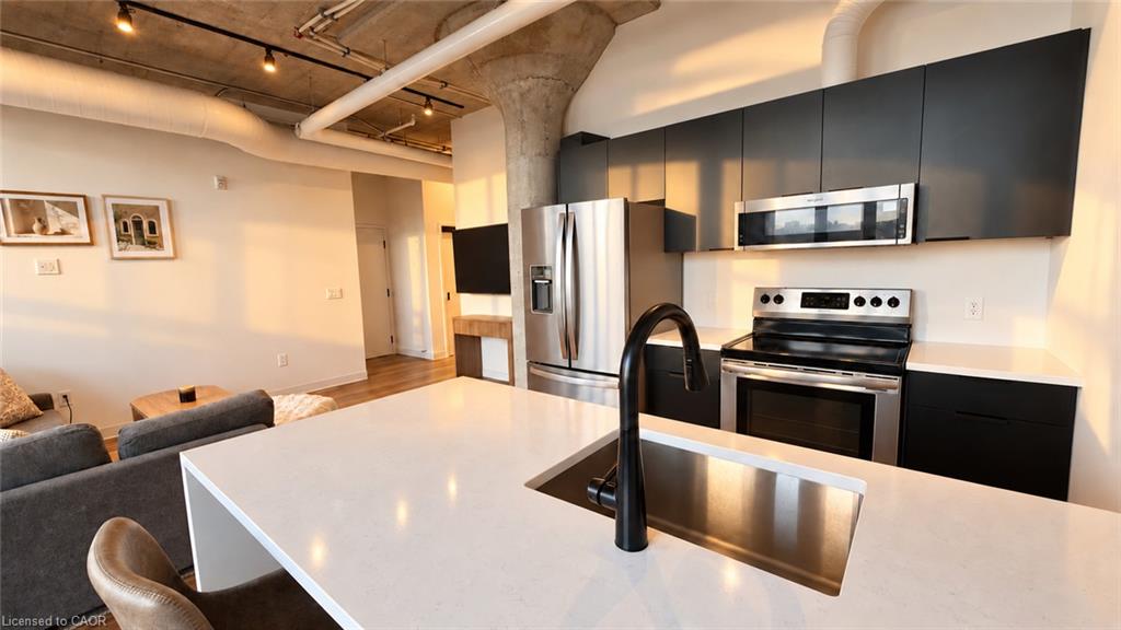 Modern kitchen with a white island, black cabinetry, stainless steel appliances, and an exposed concrete ceiling.