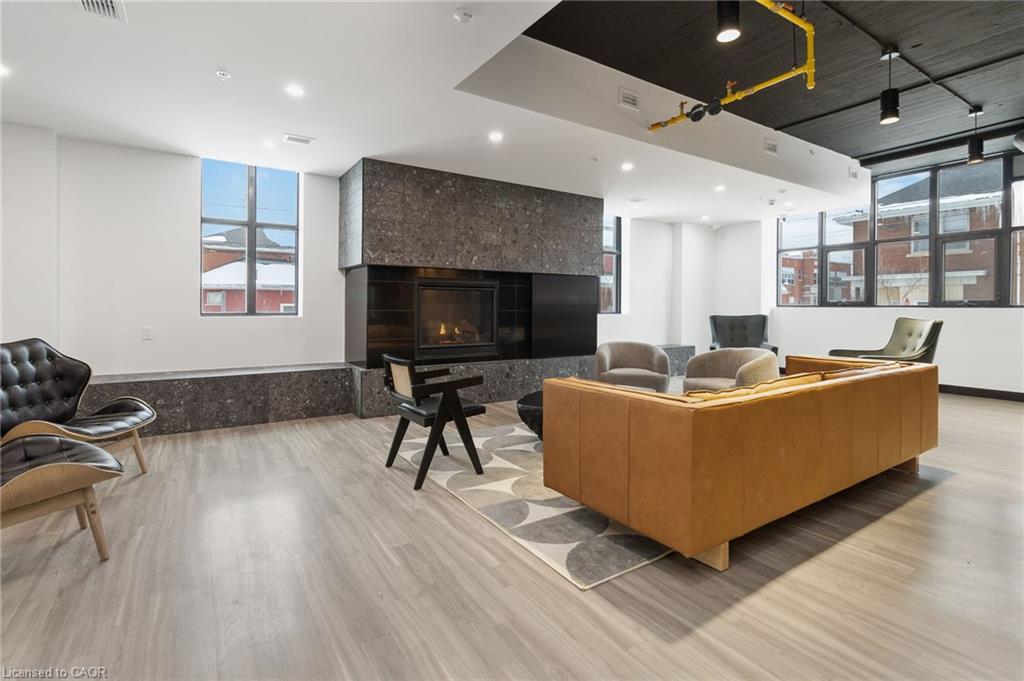 Furnished lounge with a stone fireplace, leather sofa, and large windows.