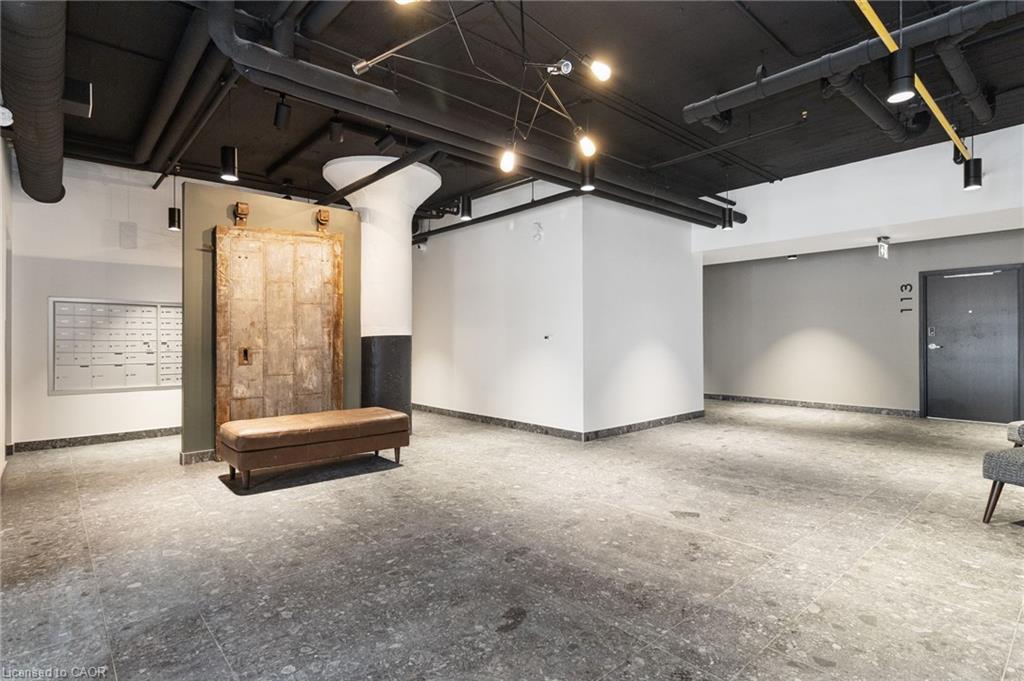 Apartment lobby with a vintage elevator door, leather bench, mailboxes, and polished concrete floor.