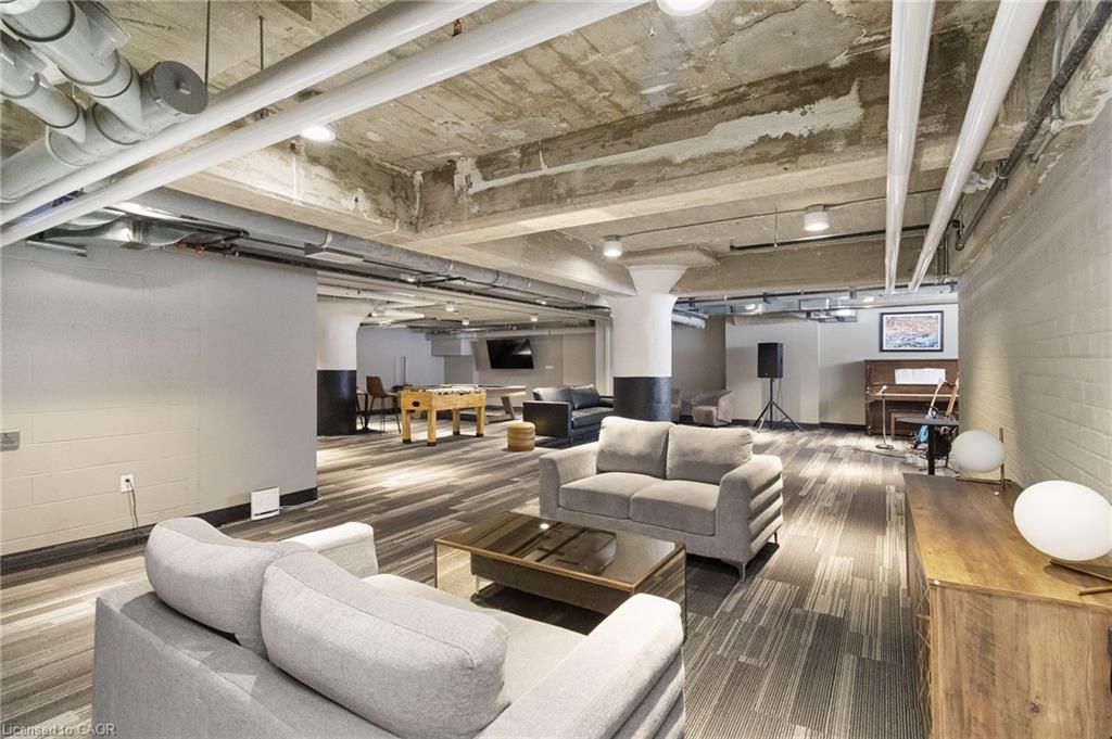 Furnished condo lounge with sofas, a foosball table, and an exposed concrete ceiling.