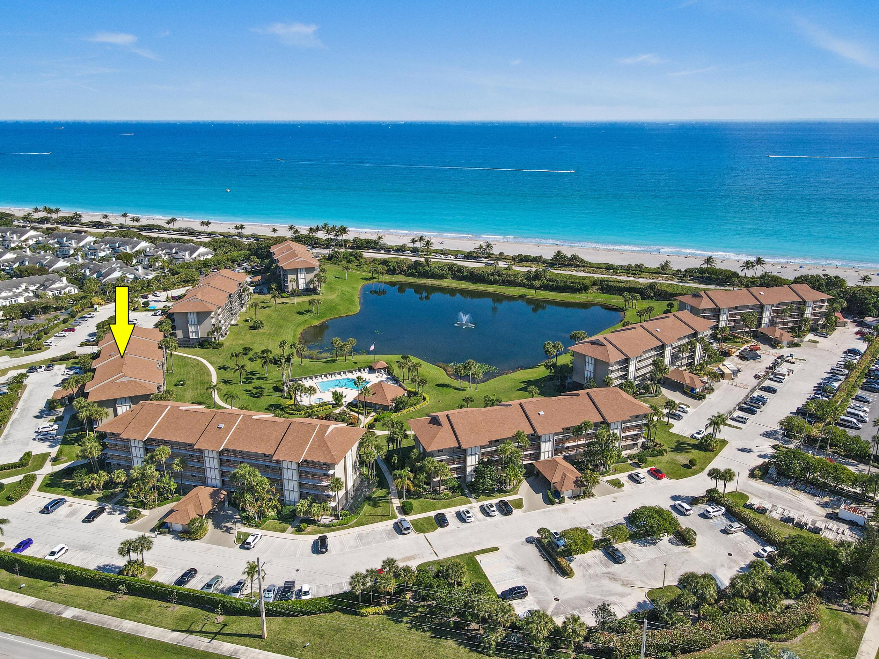 Oceanfront condominium community with a central lagoon and pool; a yellow arrow marks one building.
