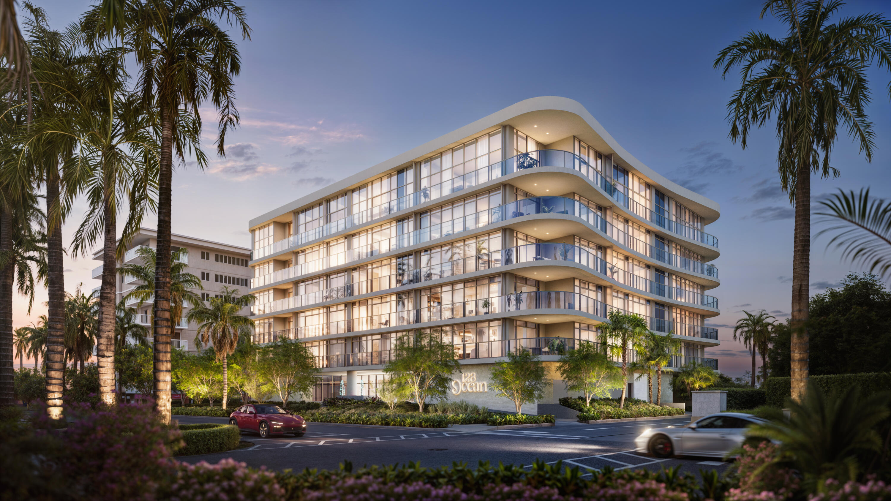 123 Ocean condominium with curved glass balconies and palm trees at dusk.
