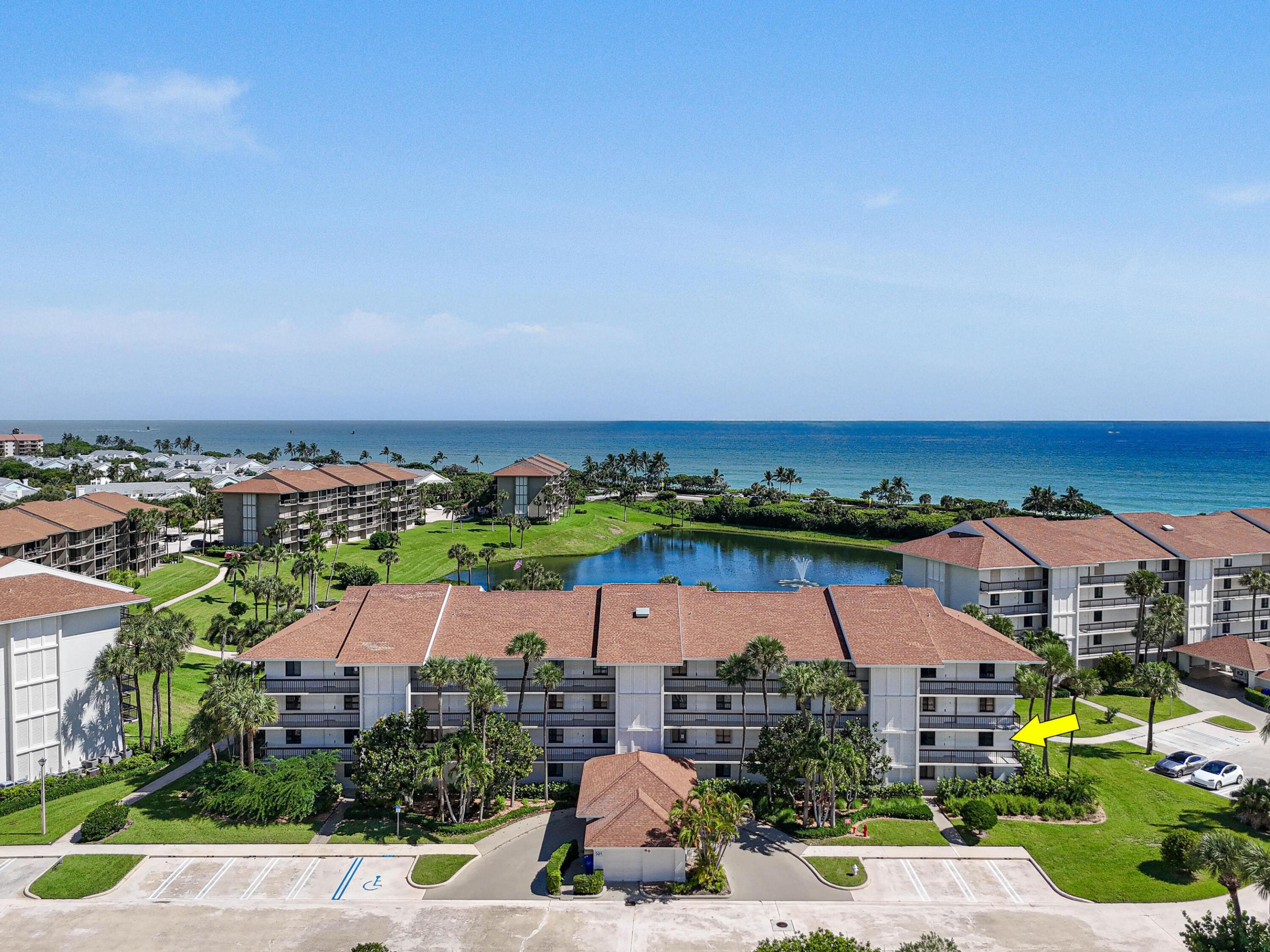 Aerial view of an oceanfront condominium, with a yellow arrow pointing to a unit in the foreground building.