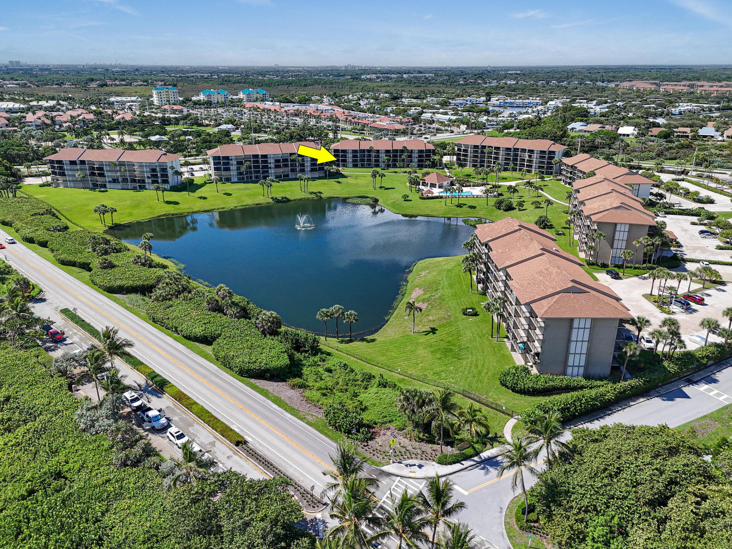 Aerial view of the condo complex, with a yellow arrow marking a building beside a pond and fountain.