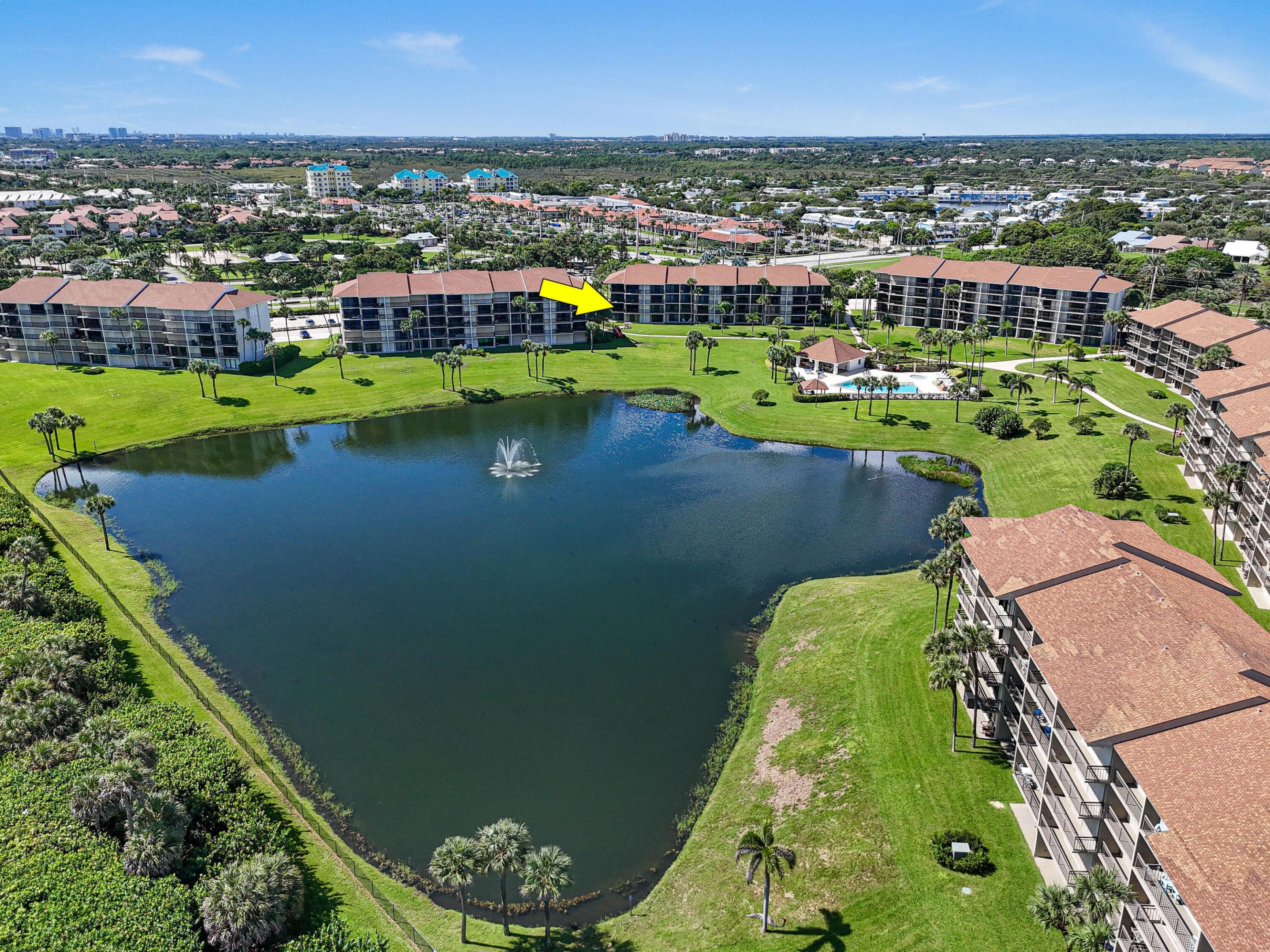 Aerial view of condominium buildings around a lake, with an arrow marking one building.