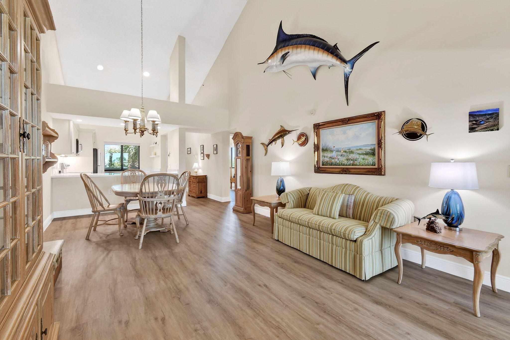 Open-plan living and dining room with a striped sofa and large mounted marlin above it.