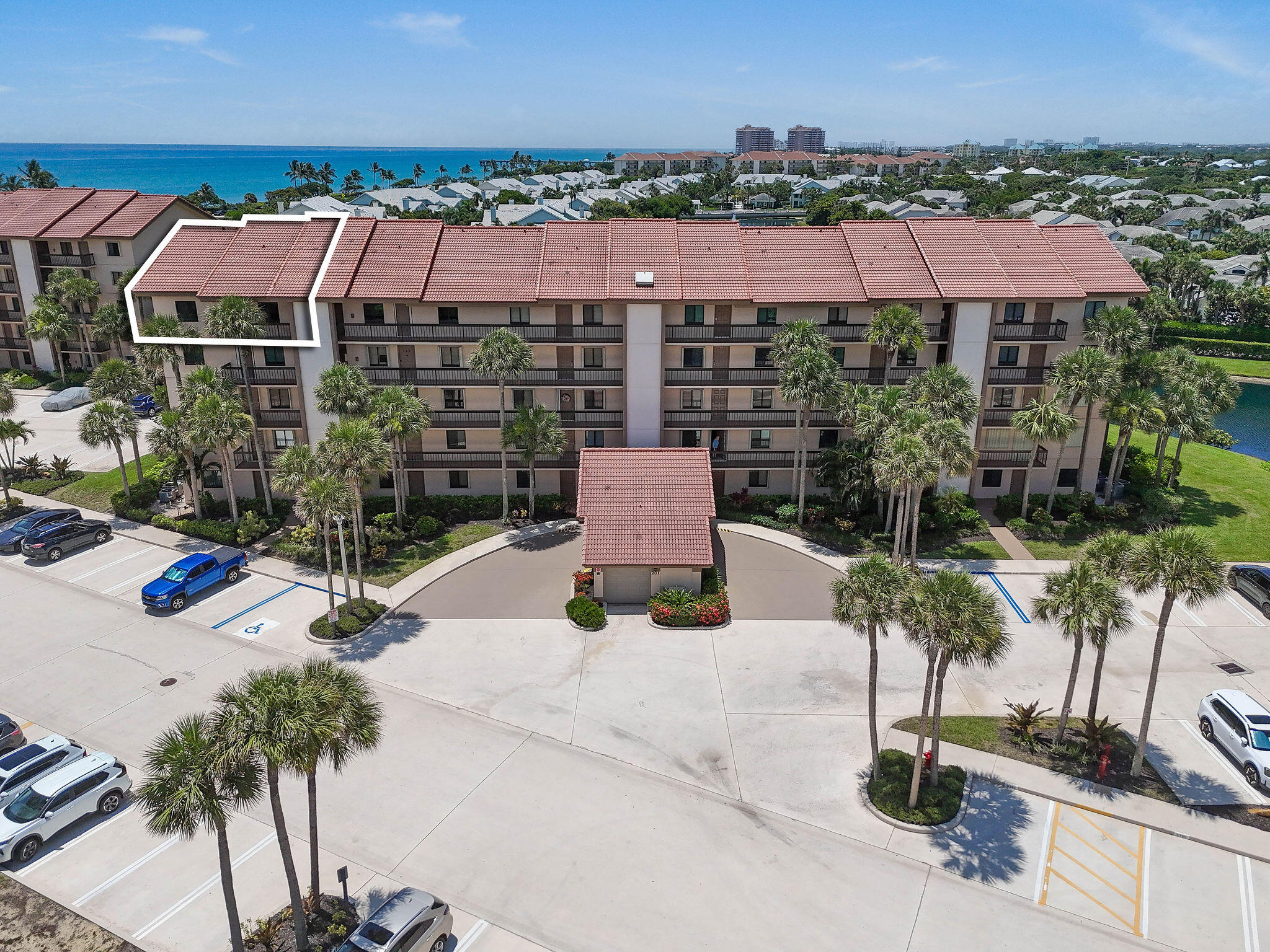 Aerial view of a beachfront condominium, with one upper-floor unit outlined and the ocean beyond.
