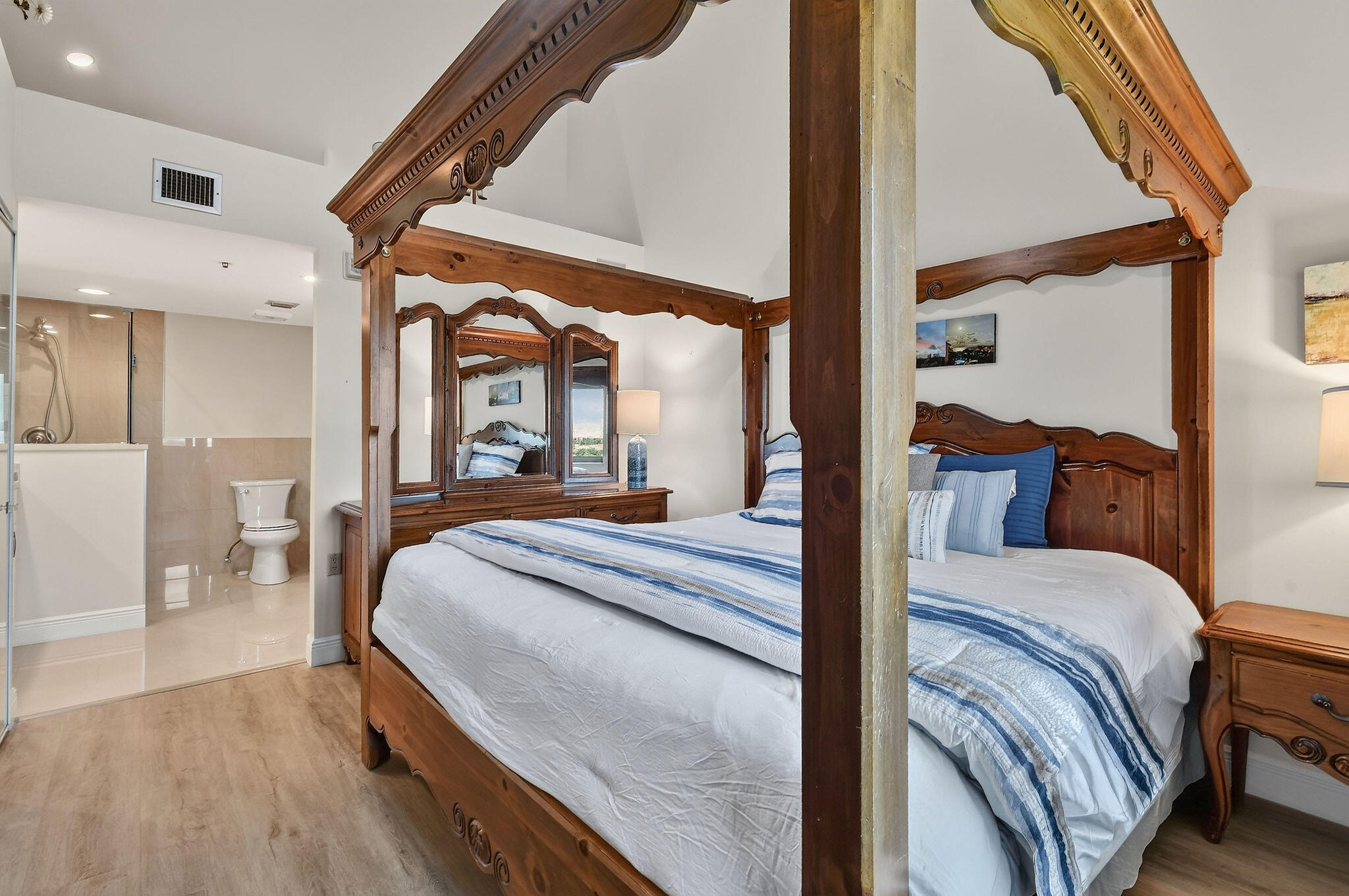 Bedroom with an ornate wooden canopy bed, blue-and-white bedding, and an en-suite bathroom.