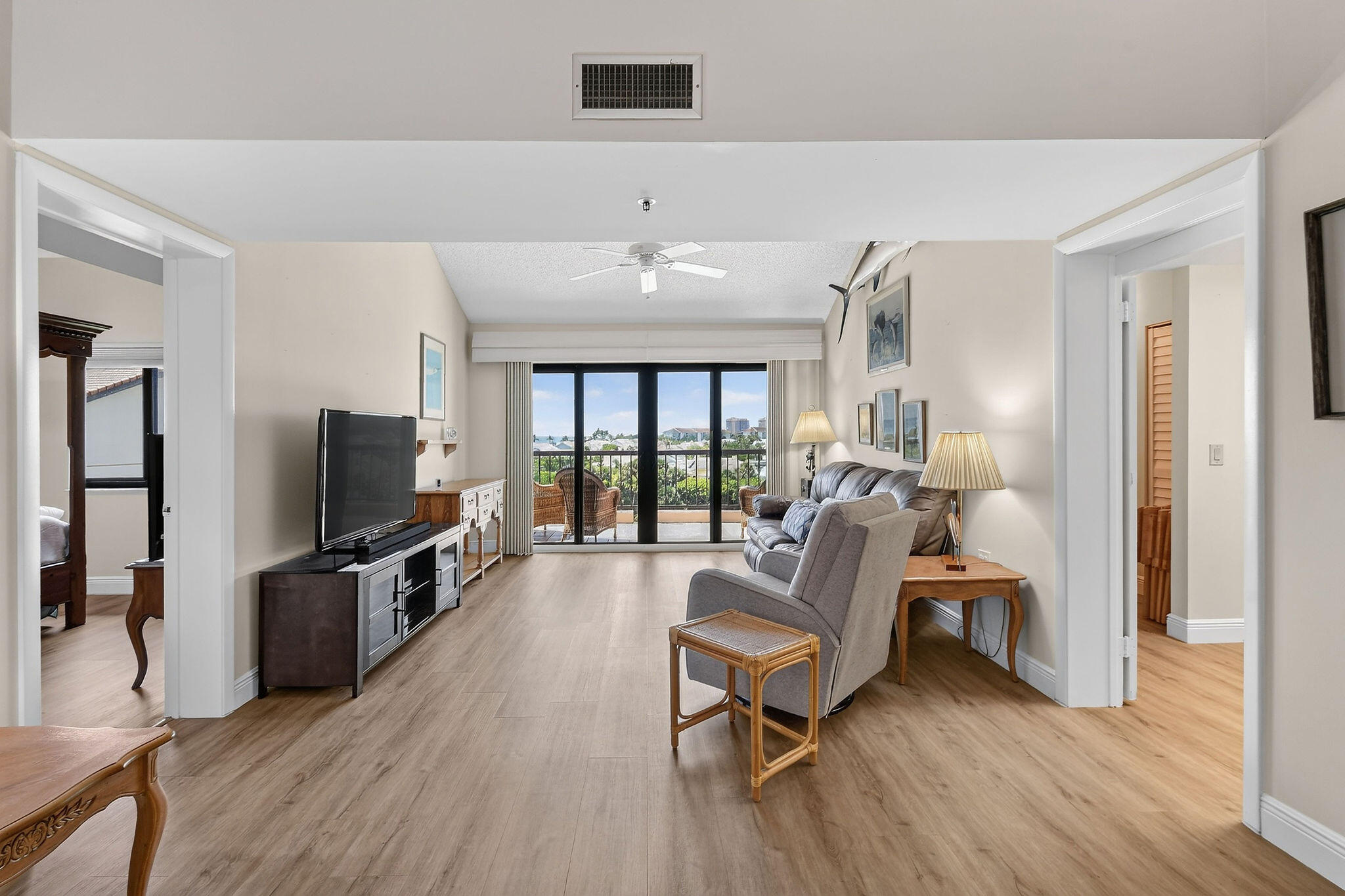 Furnished living room with gray seating and sliding glass doors opening to a balcony.