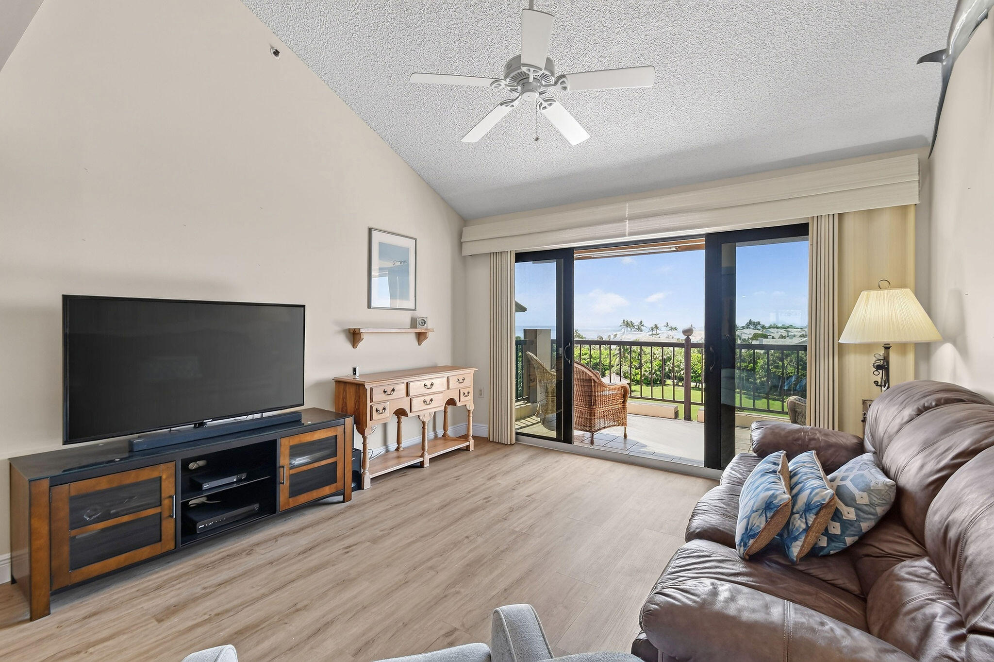 Living room with leather sofa and sliding doors opening to a balcony with ocean views.