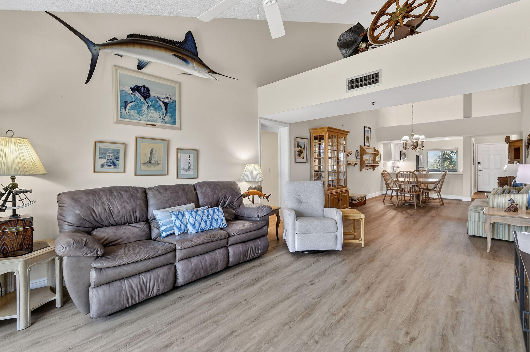 Open-plan living room with a gray leather sofa and prominent marine-themed decor.