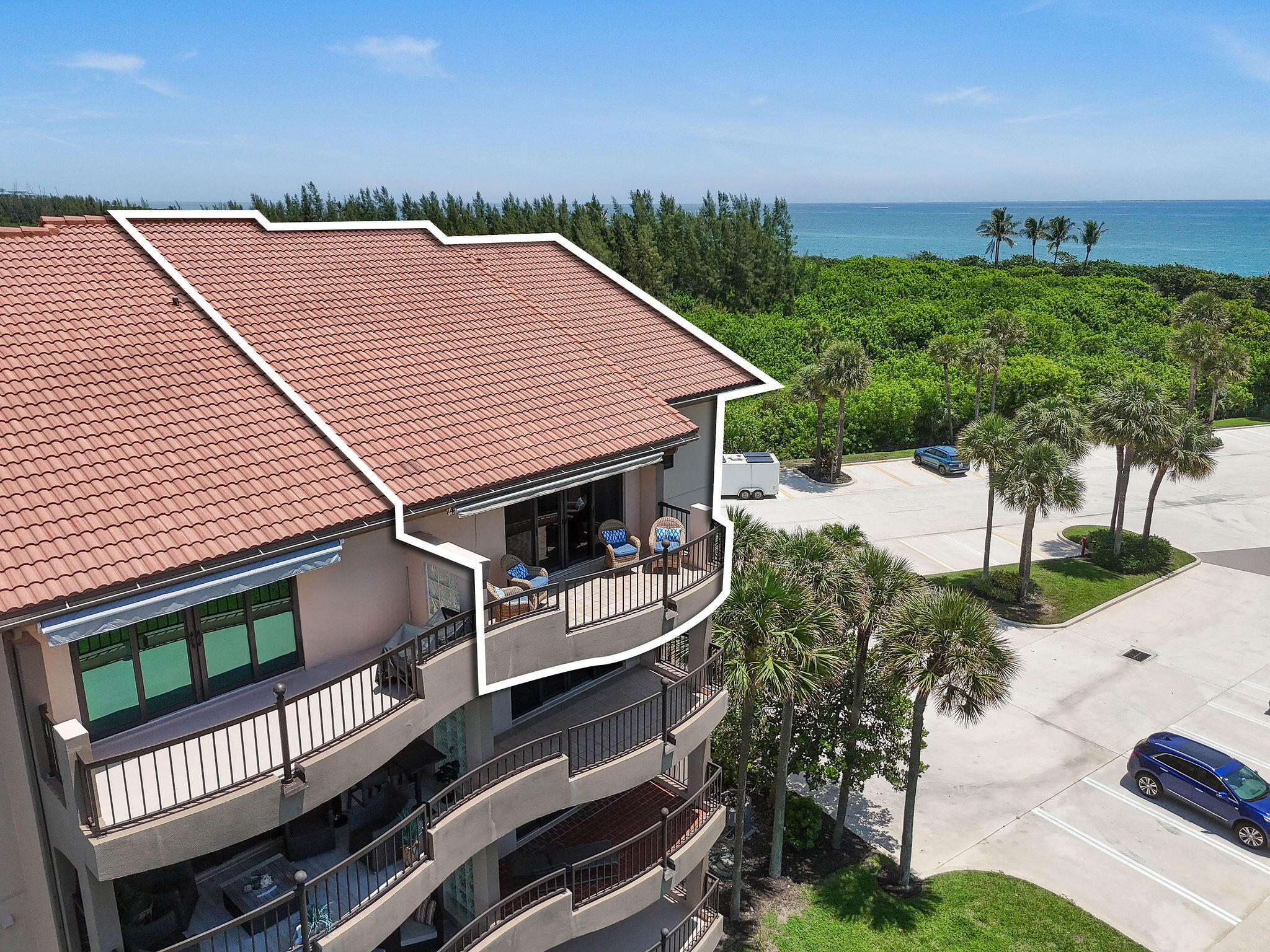 Beachfront condominium unit outlined in white, with balconies overlooking palm trees and the ocean.