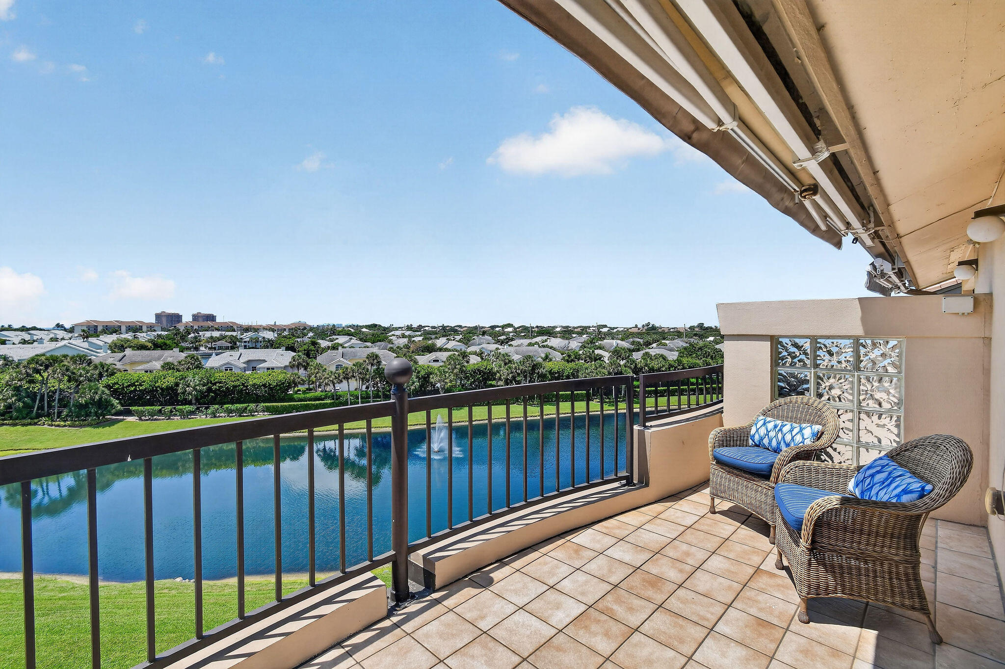 Furnished balcony overlooking a waterway and landscaped residential grounds.