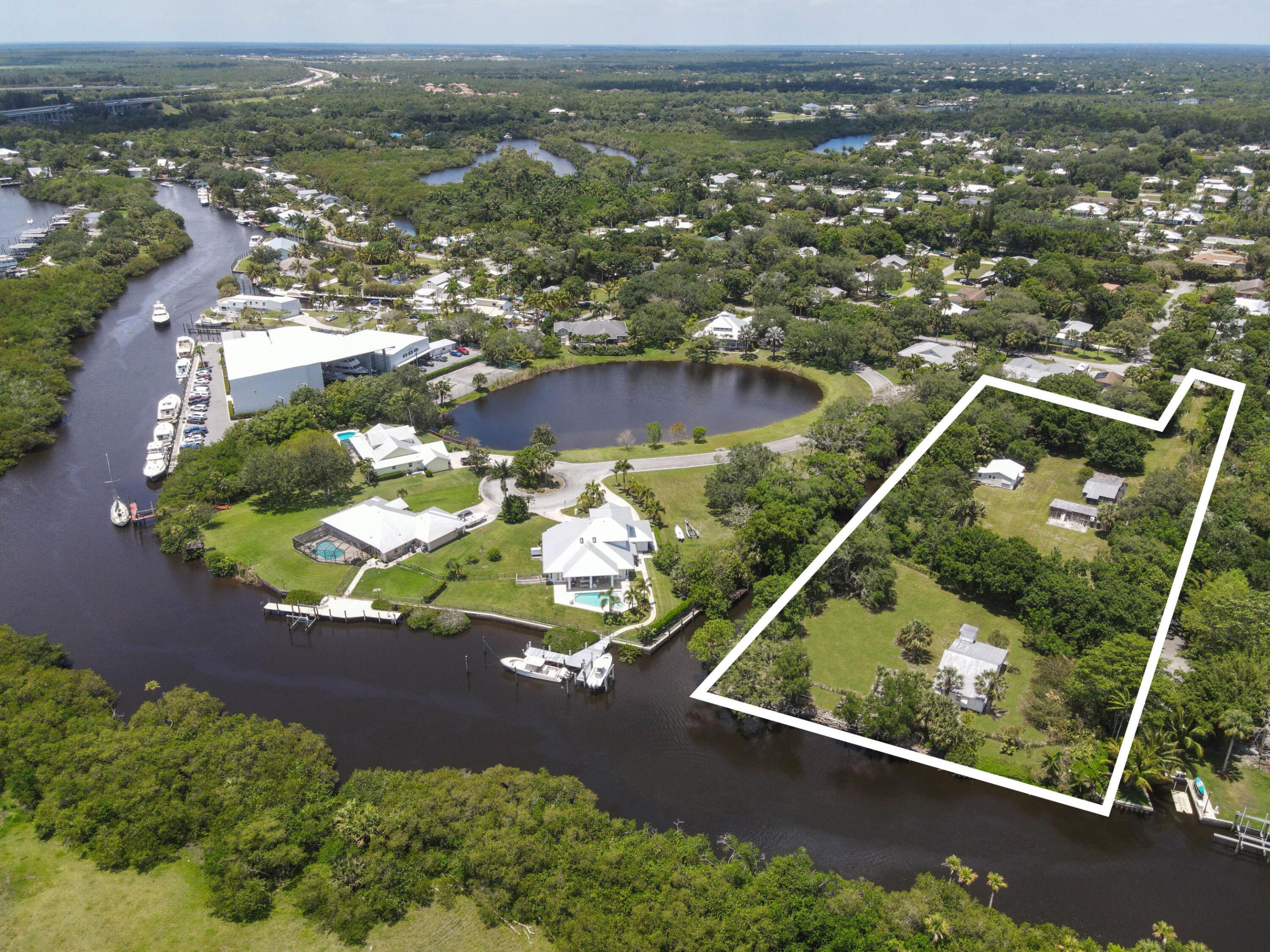 Aerial view of a canal-front property outlined in white, with several buildings and open lawn.