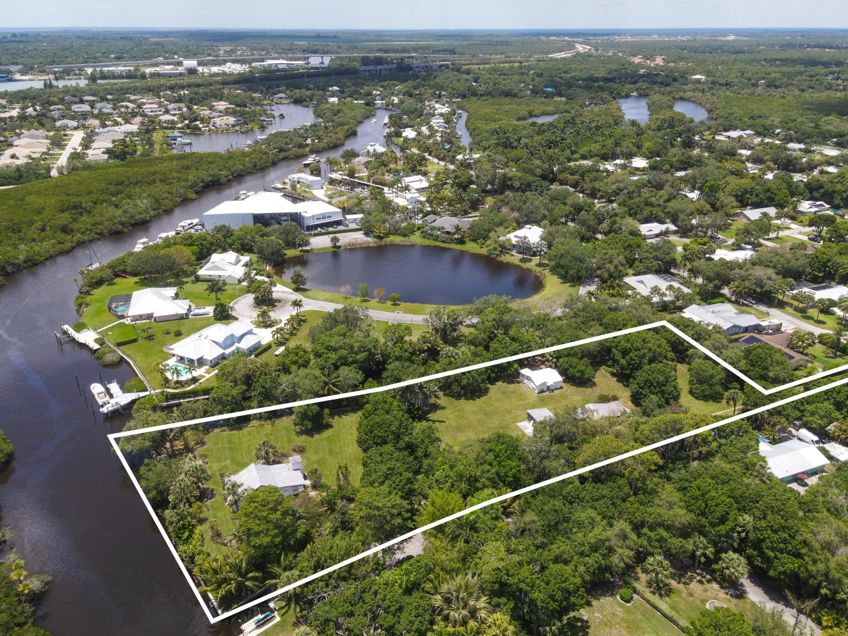 Aerial view of a wooded waterfront parcel outlined in white, with small structures and a canal along its edge.