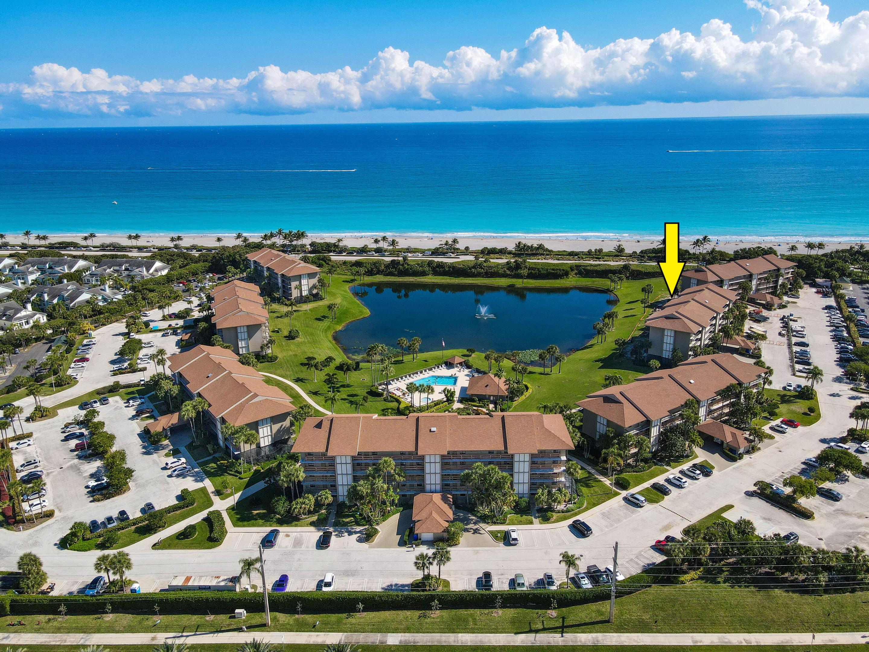 Aerial view of a beachfront condominium complex, with a yellow arrow marking a building beside a lagoon.
