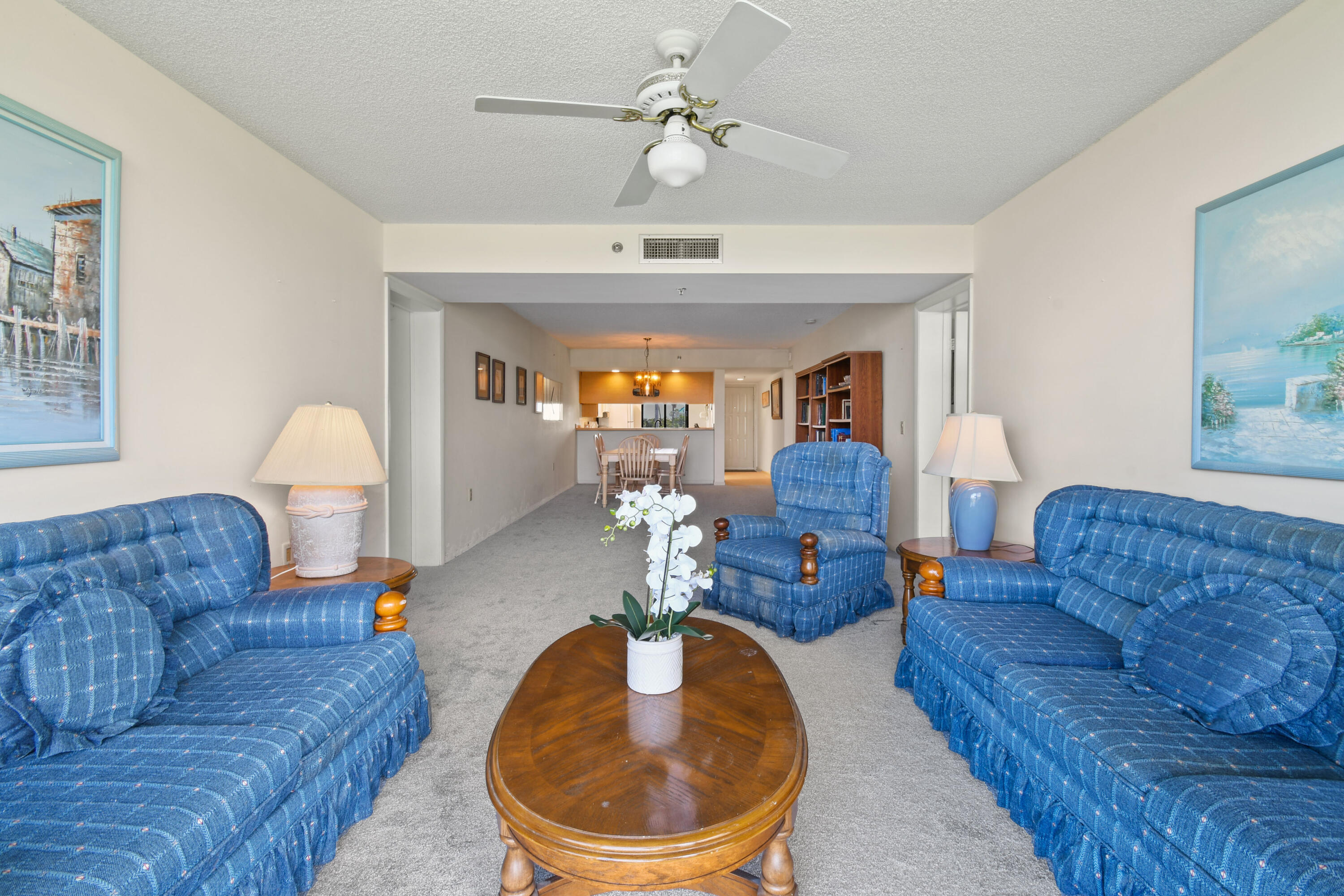 Furnished living room with blue sofas, a wooden coffee table, and a dining area beyond.