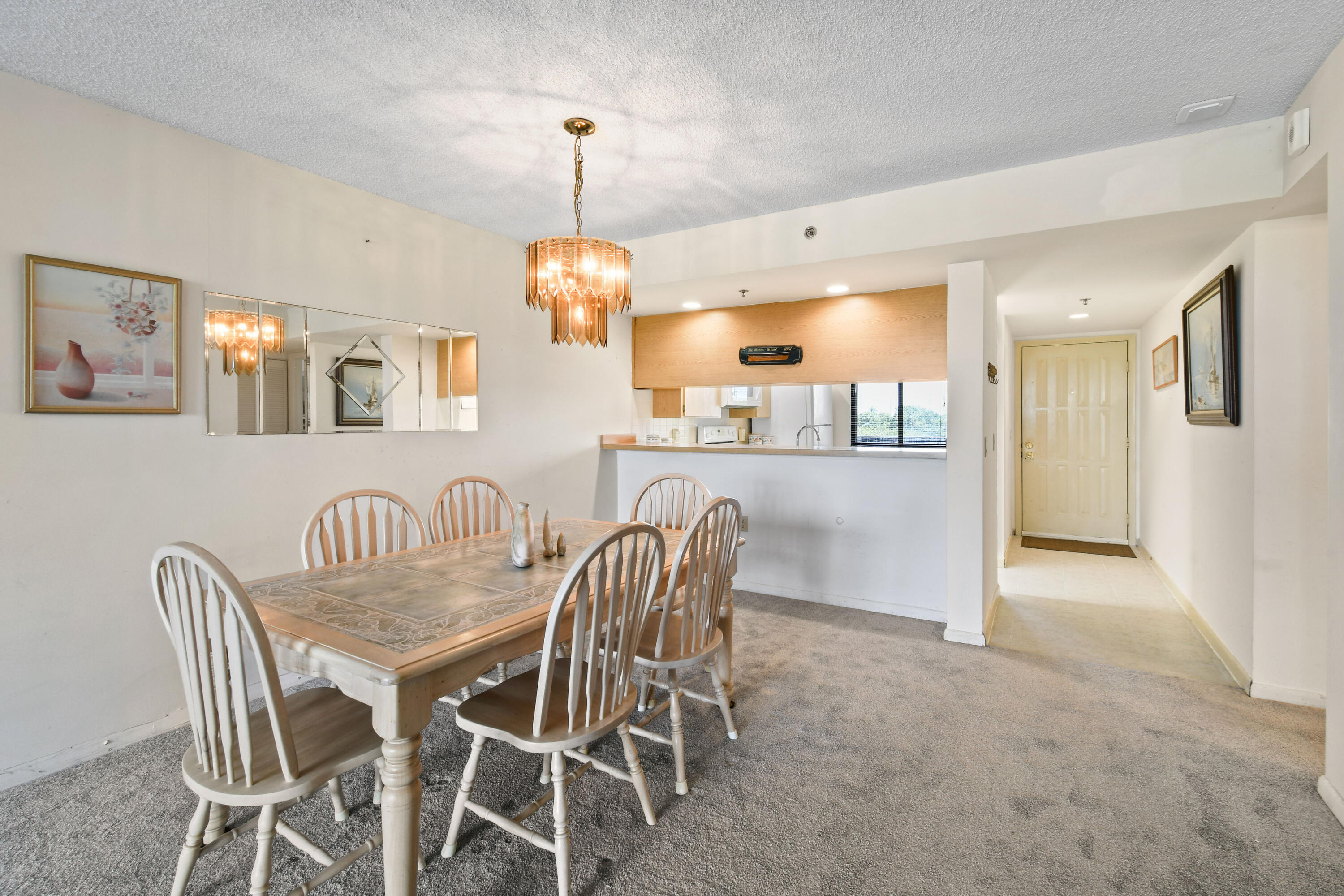 Dining room with a wood table, spindle-back chairs, pendant light, and an open view into the kitchen.
