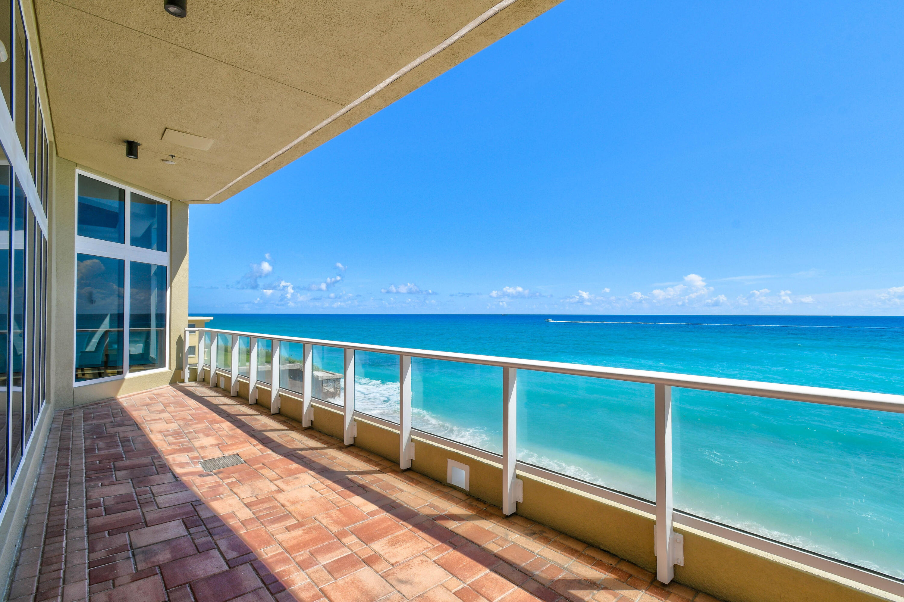 Tiled oceanfront balcony with glass railing and expansive turquoise water views.