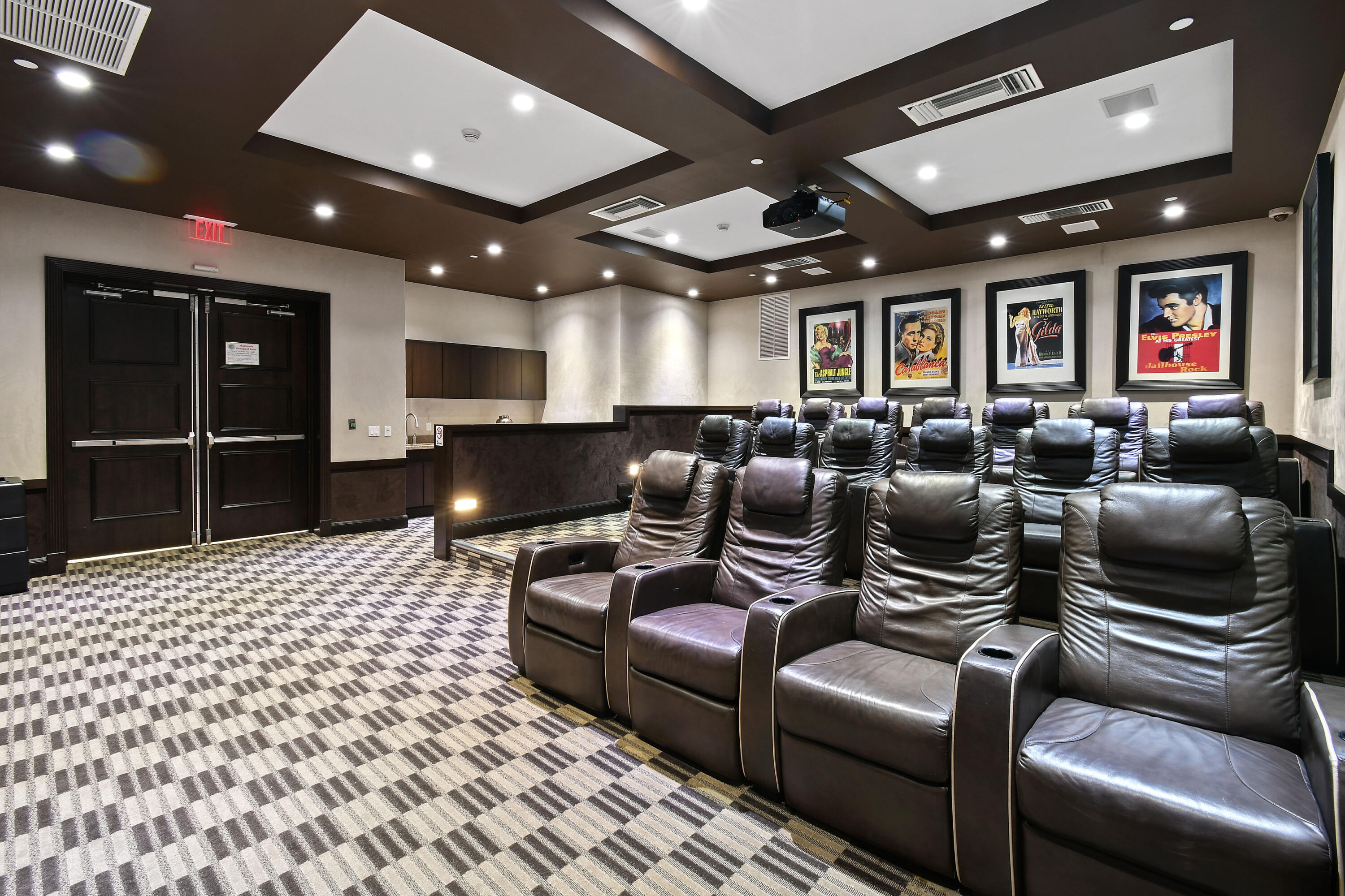 Screening room with rows of leather recliners and framed classic movie posters.