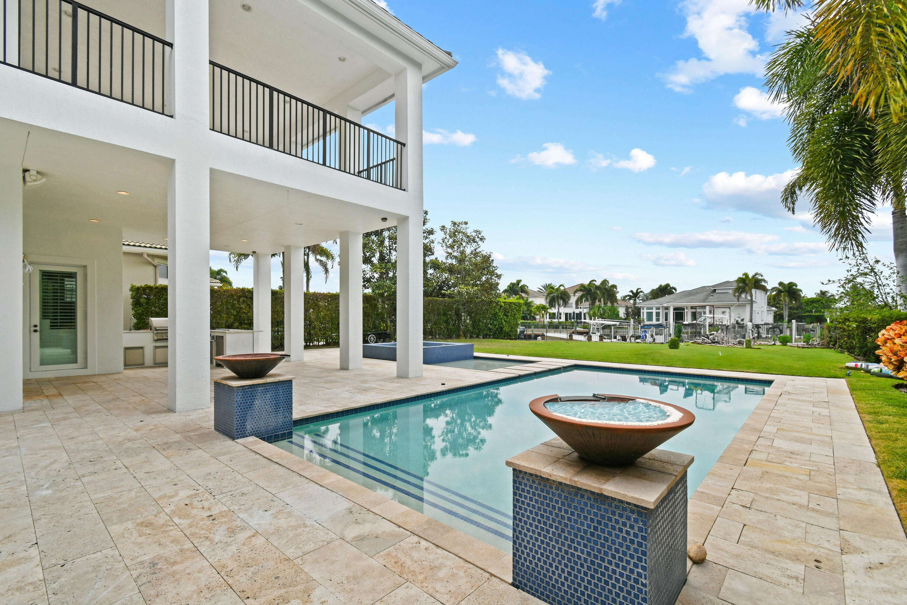 Swimming pool beside a white home, with a raised spa and covered patio.