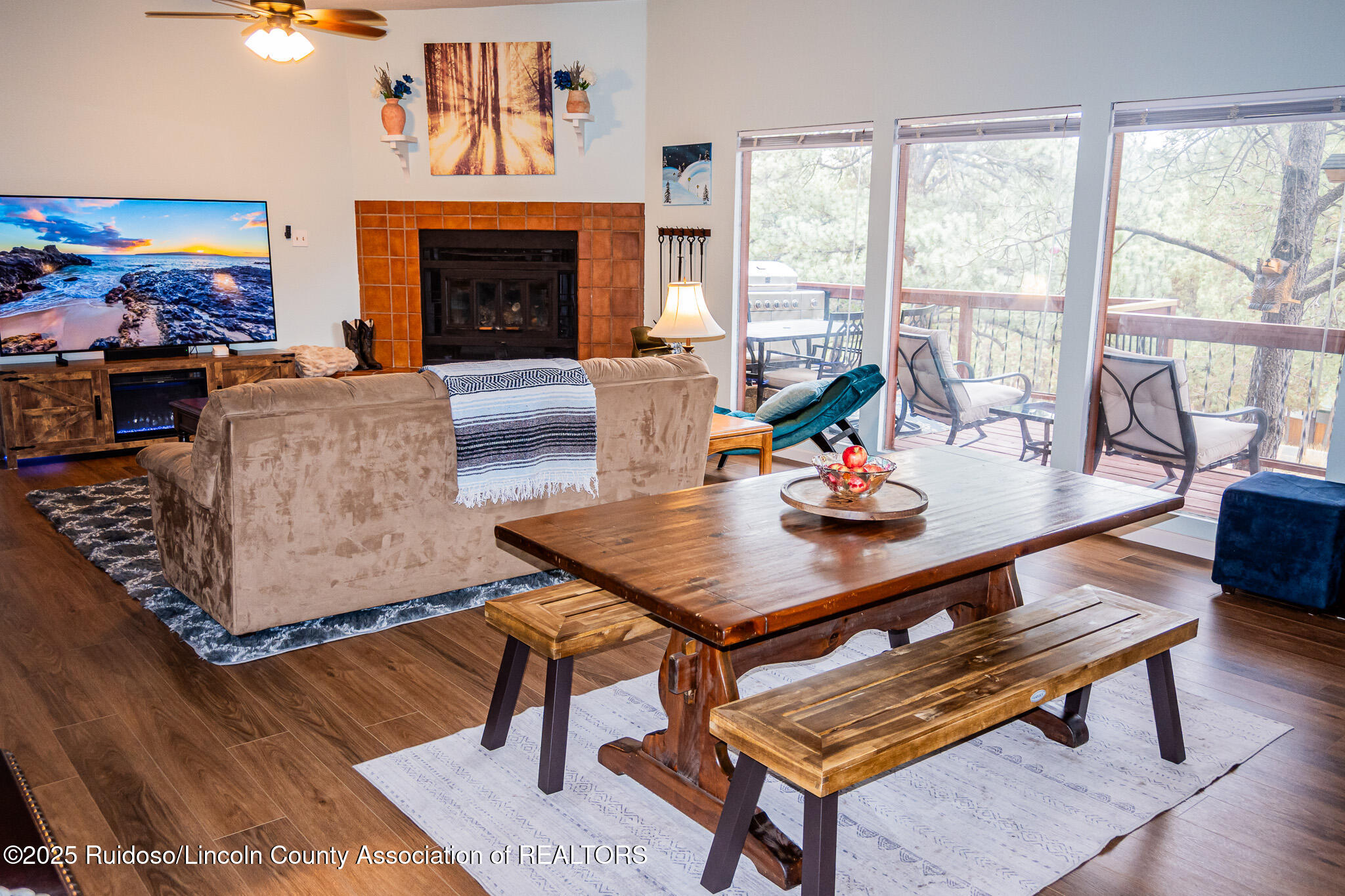 Furnished living room with a tiled fireplace and sliding glass doors opening onto a tree-lined deck.
