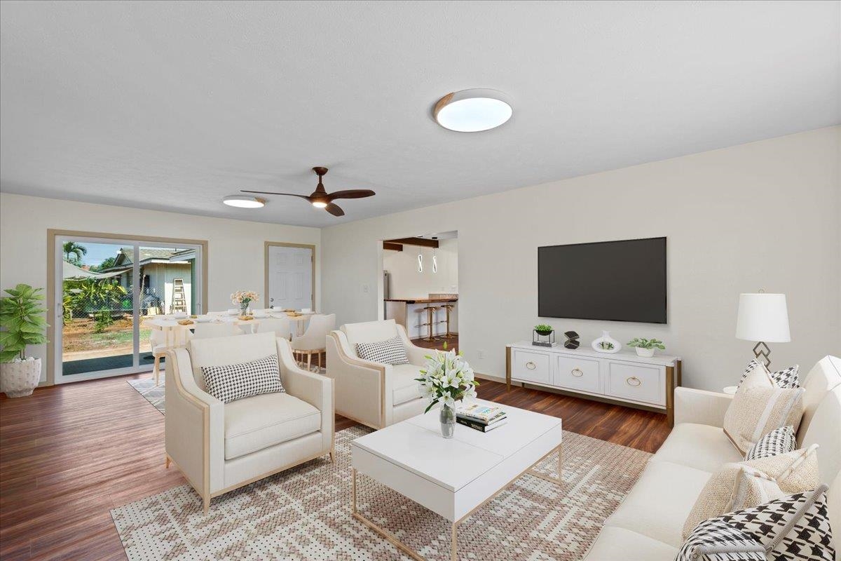 Staged living room with white seating, patterned rug, wood floors, and sliding glass doors.
