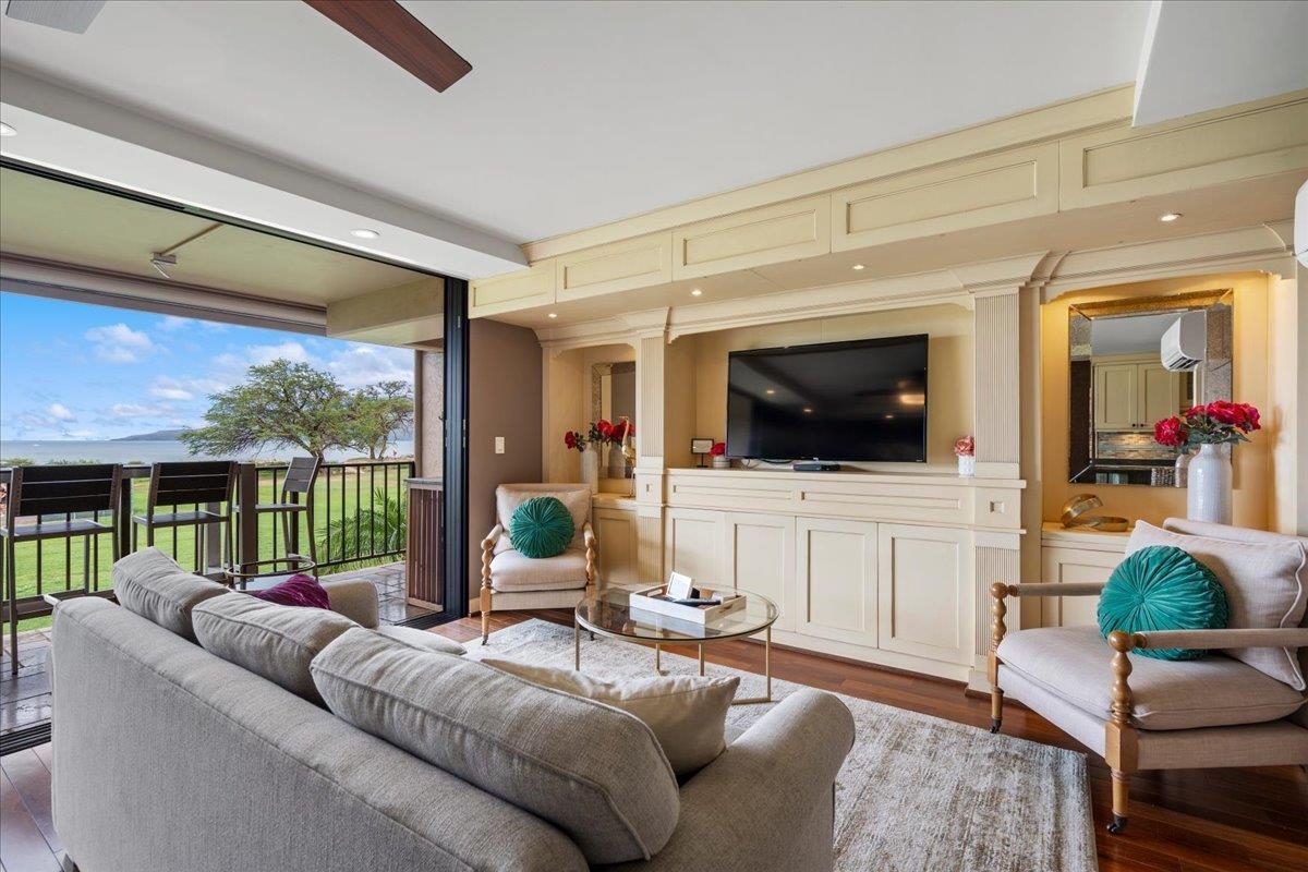 Living room with cream built-ins and ocean views through open sliding doors.